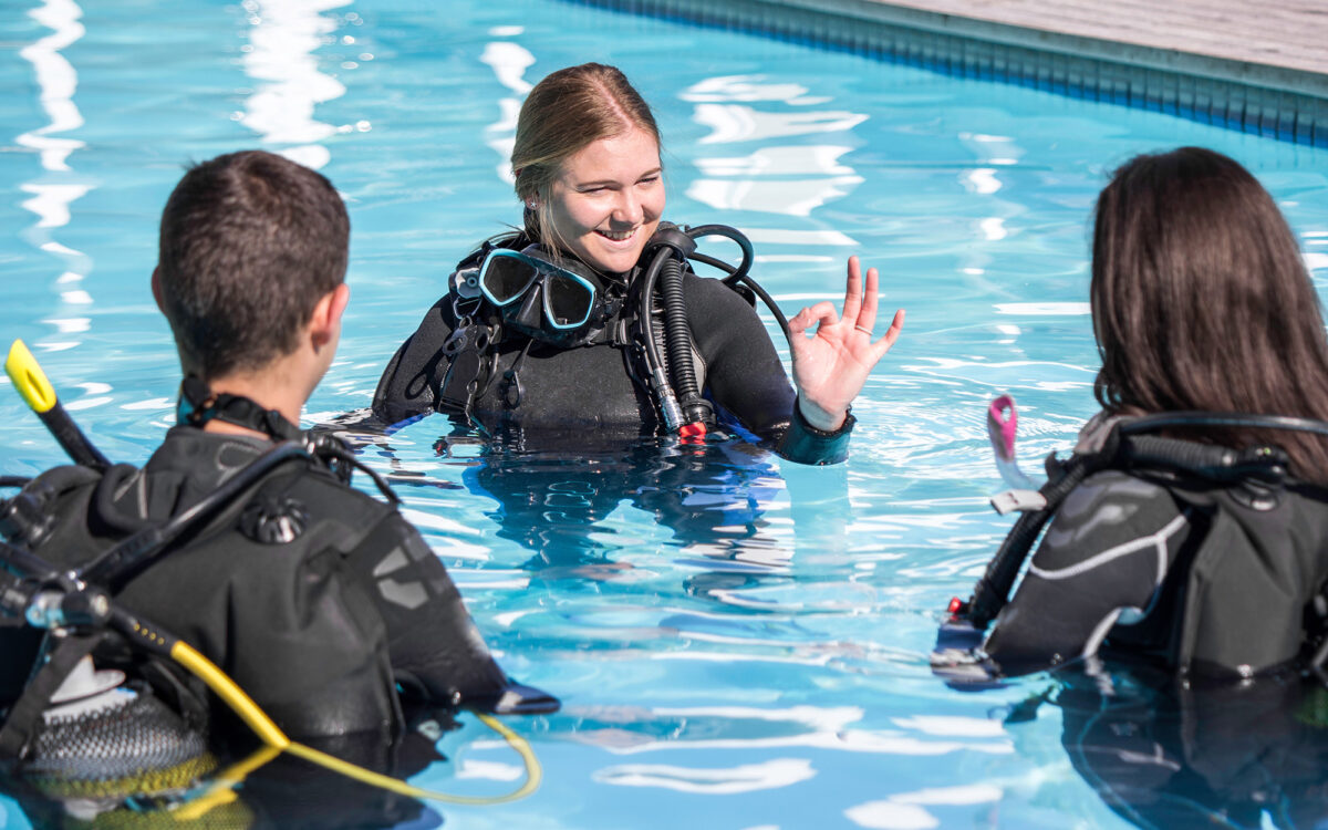 Scuba dive training in the pool with an instructor showing the OK sign to two students